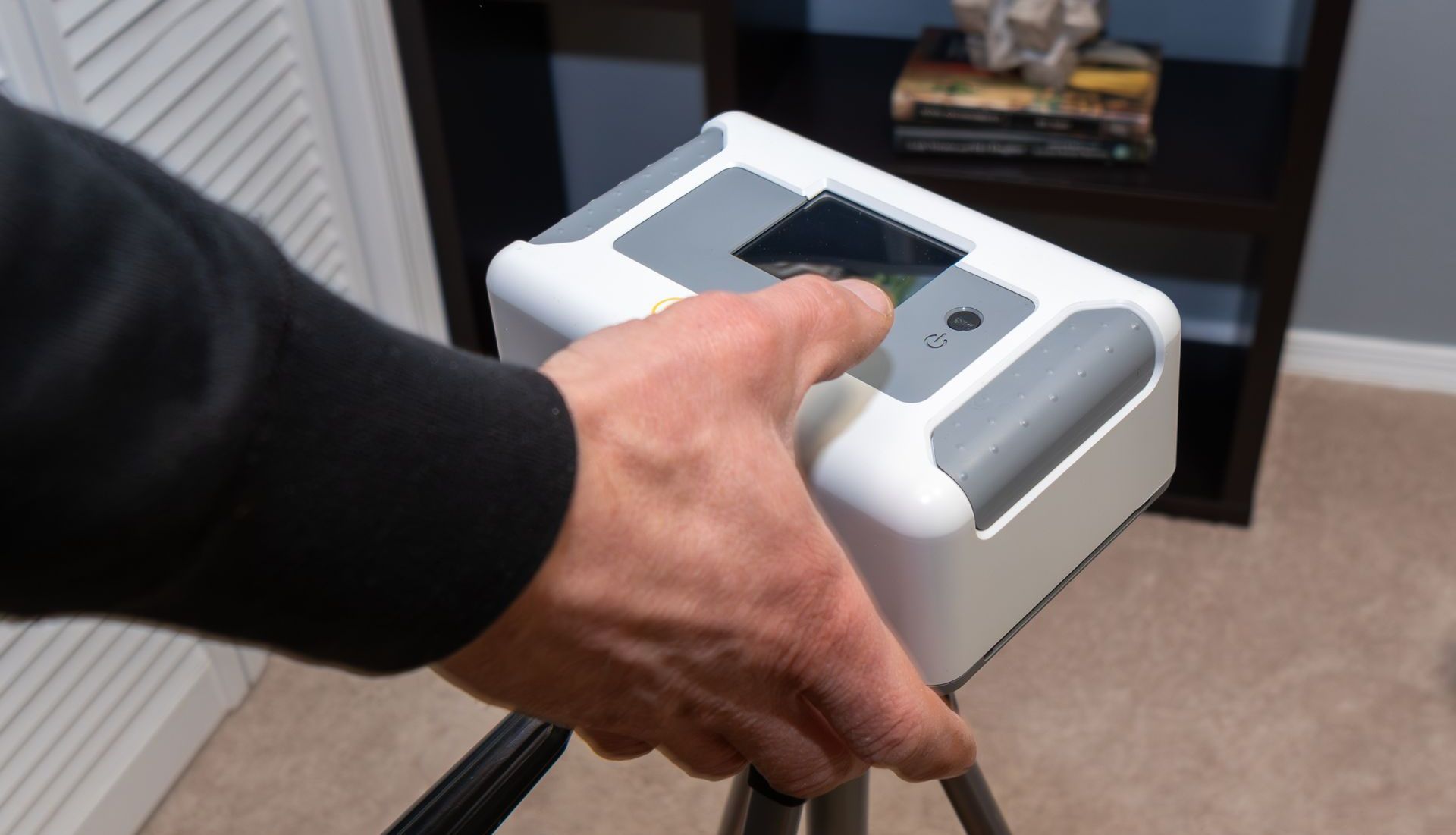 A person is holding a radon testing device on a tripod.