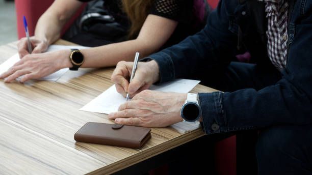 A divorce lawyer is assisting a couple as they fill out legal forms during their divorce process.