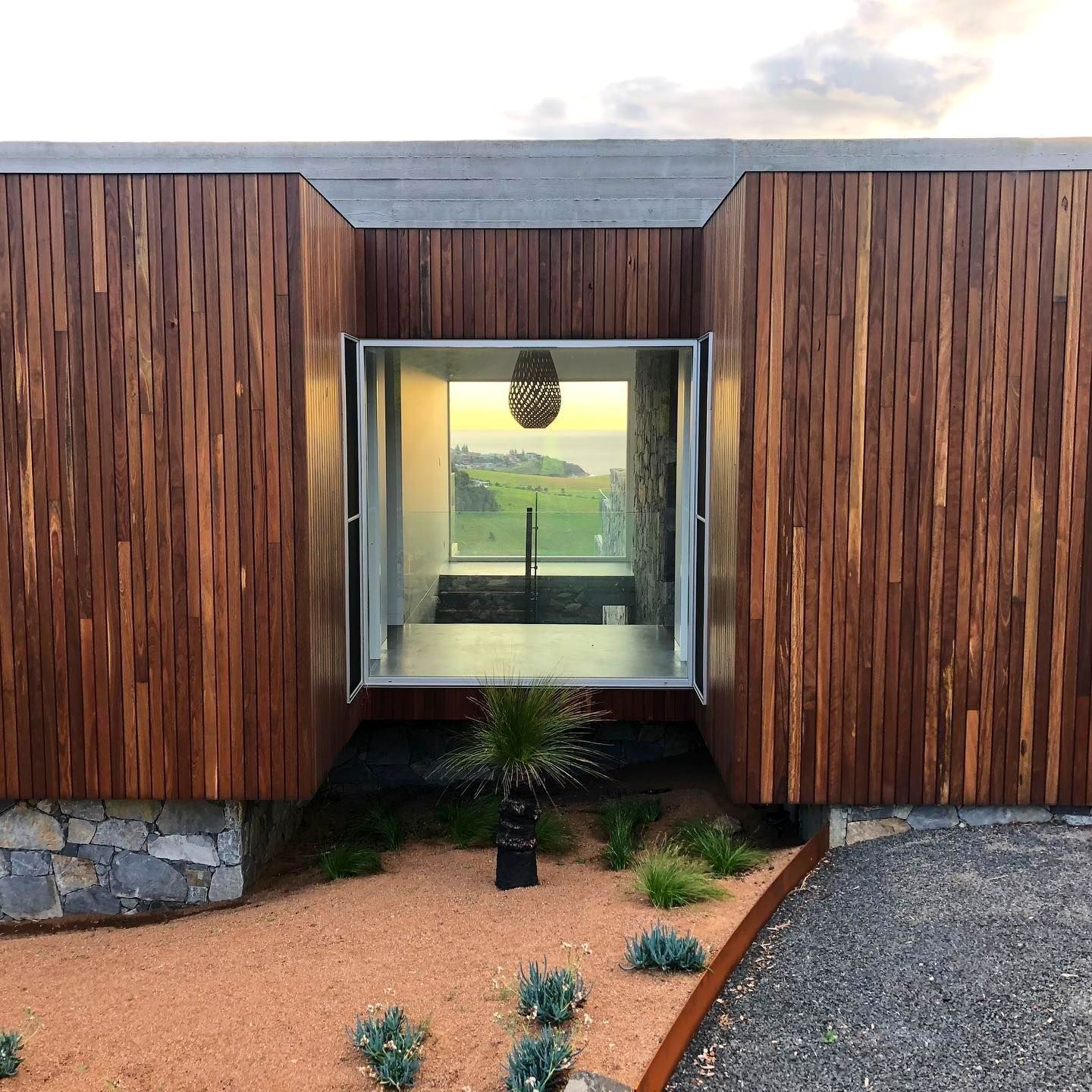 Wooden modern building with an open window revealing a pool and green fields.