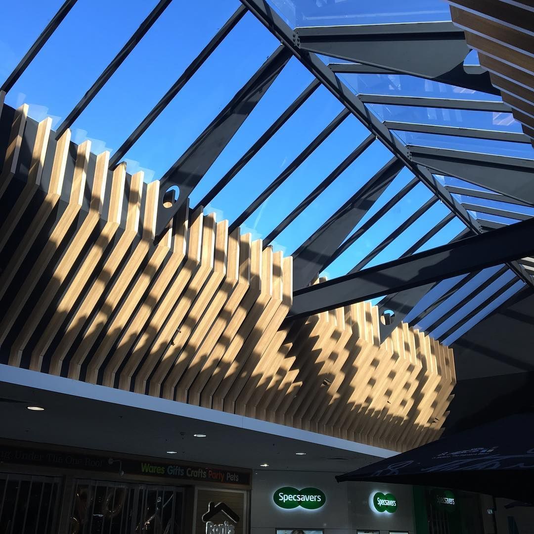 Skylight with wooden slats and beams, blue sky visible. Retail shop signage below.