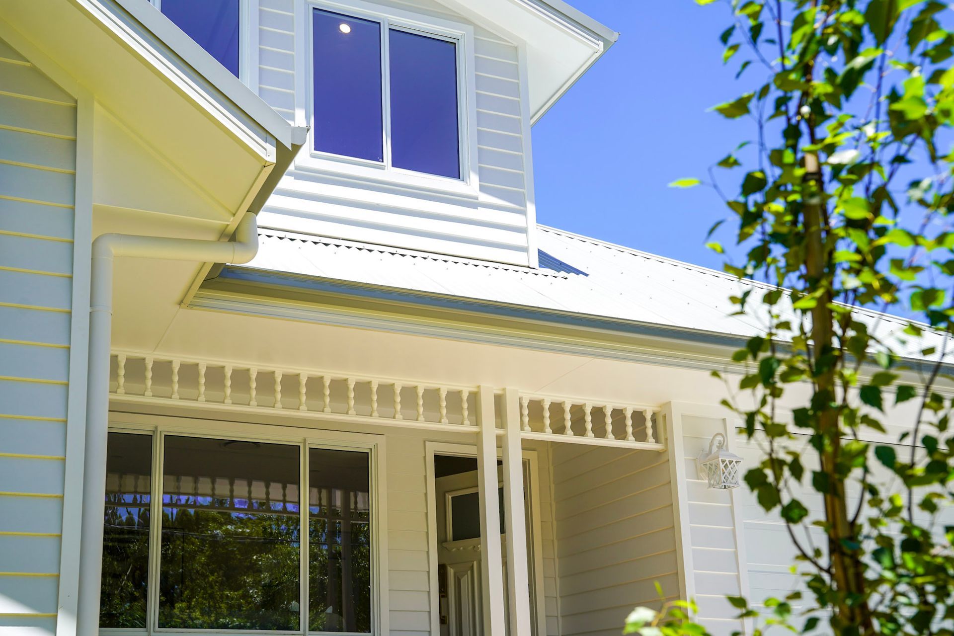White house exterior with blue windows and a clear sky.