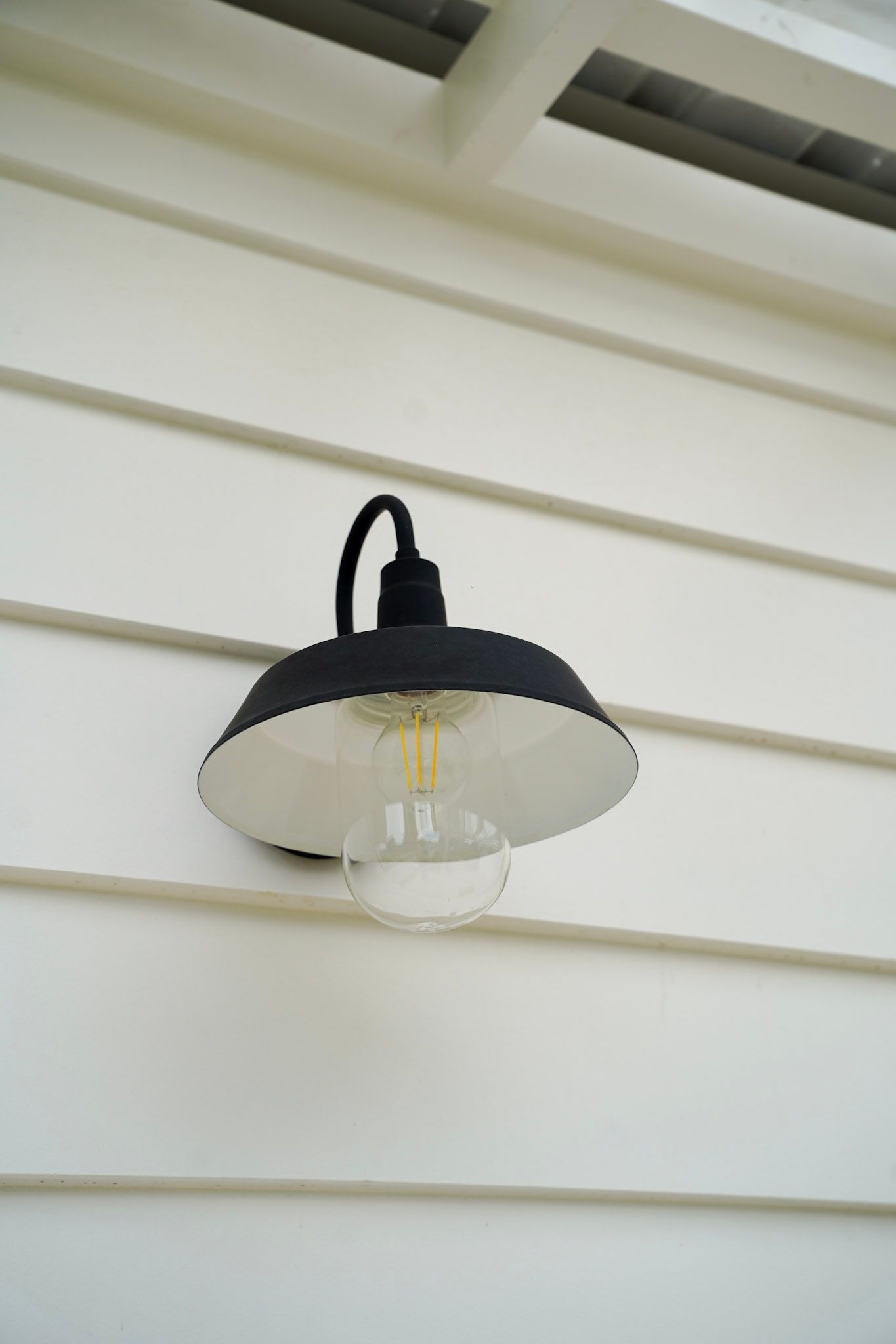 Black outdoor light fixture on white siding.