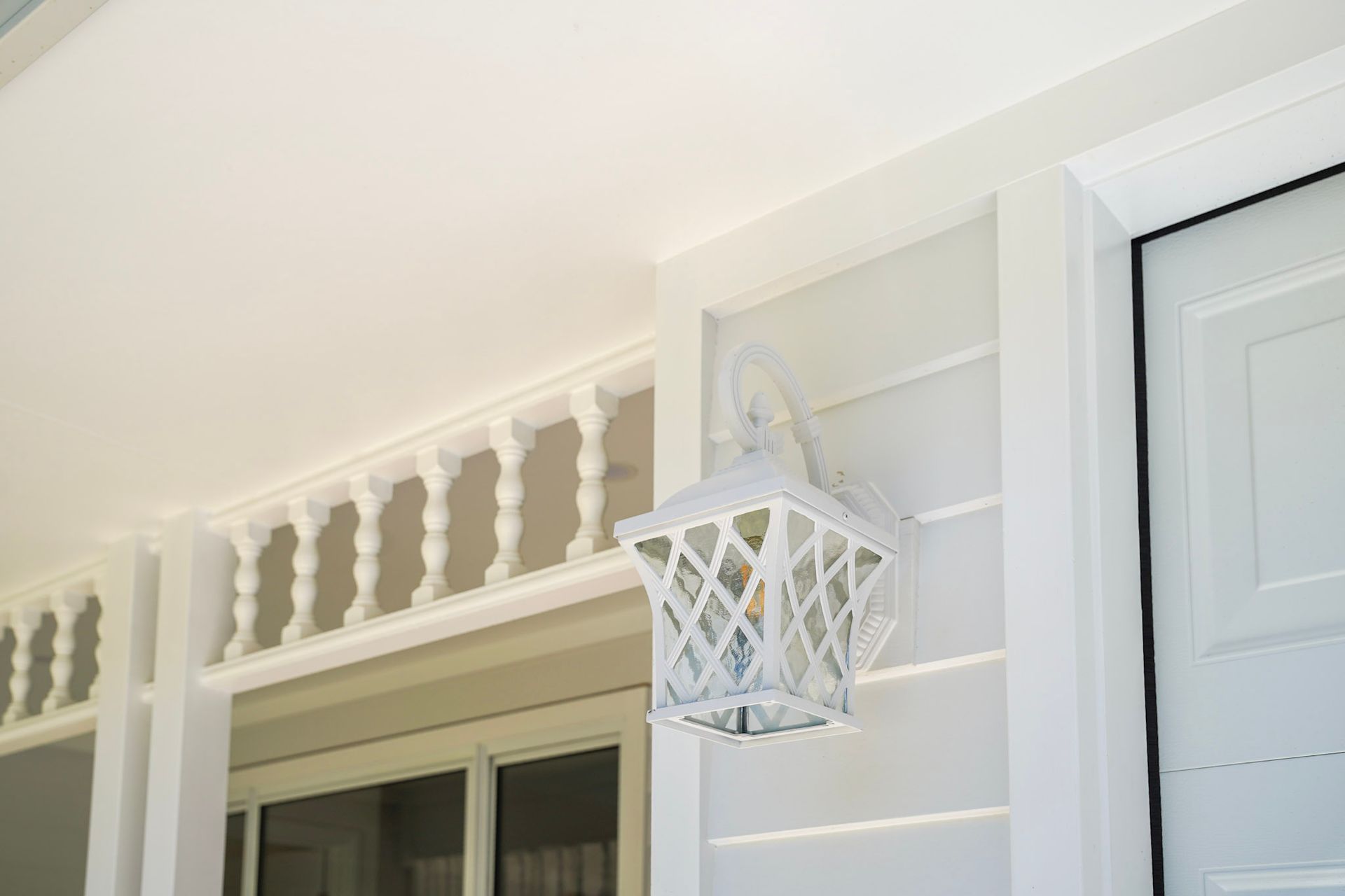 White porch with balustrade and lantern.