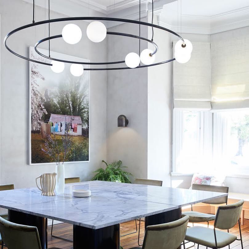 Dining room with marble table, modern light fixture, artwork, and seating.