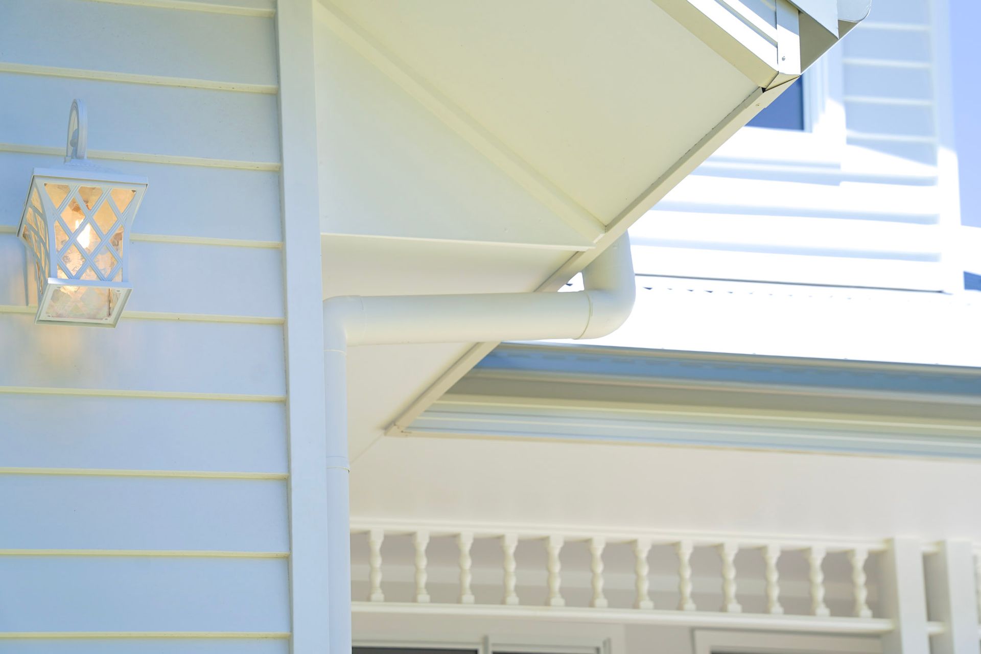 White house exterior with siding, a lamp, and gutter.