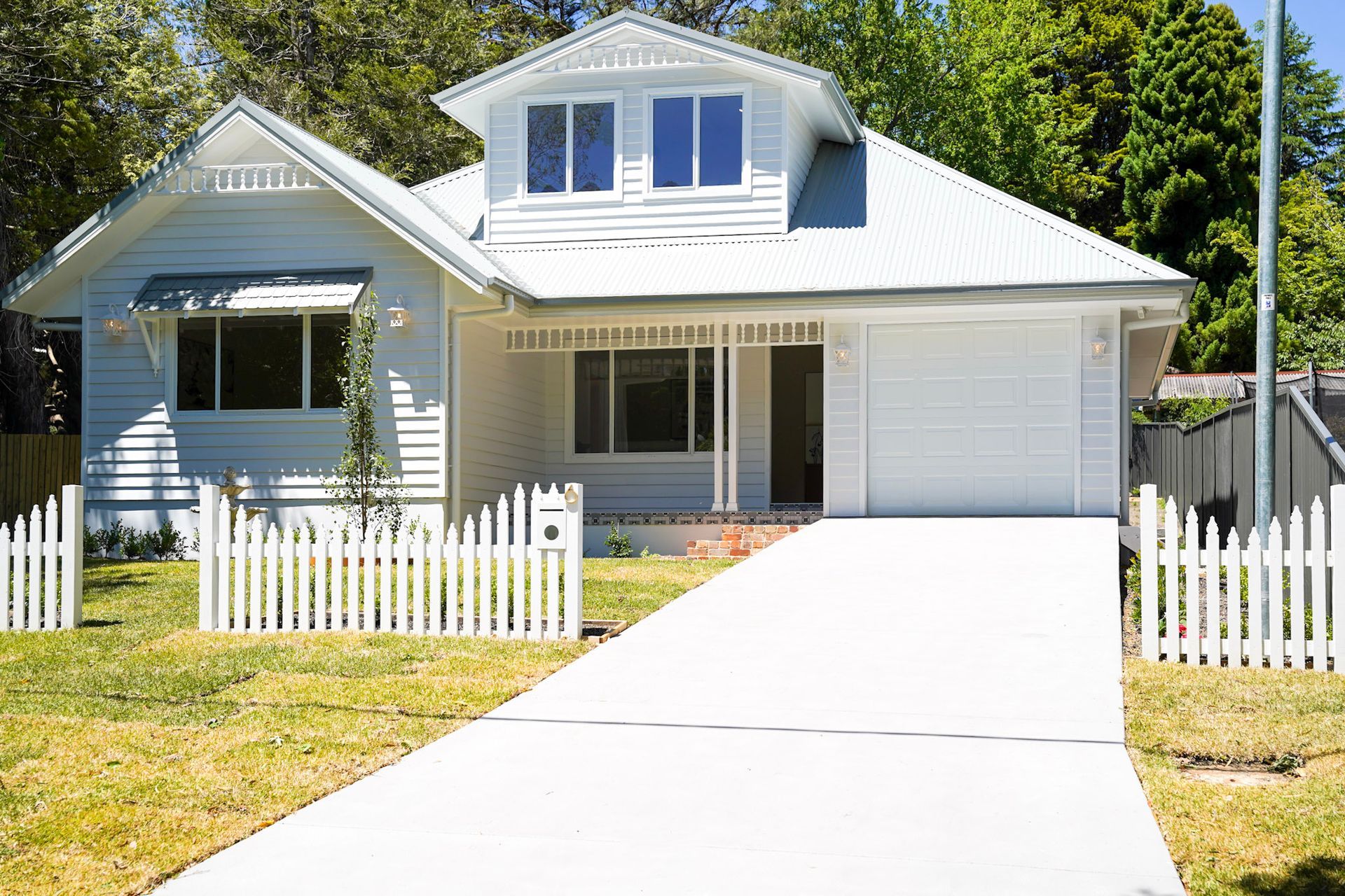 White house with picket fence and driveway.