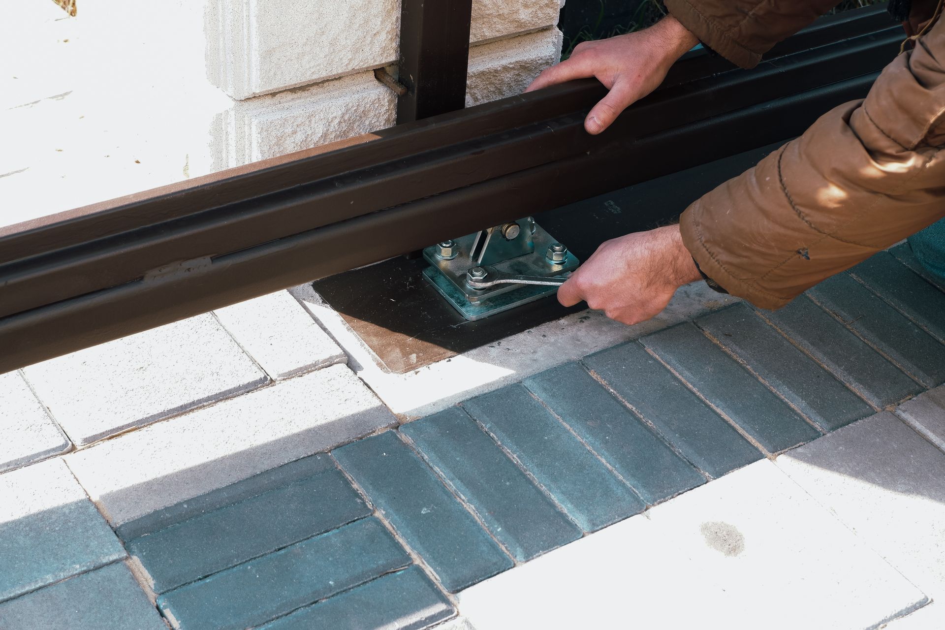 A man is working on a sliding glass door with a wrench.