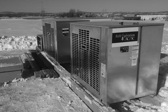 Une photo en noir et blanc de deux climatiseurs dans la neige.