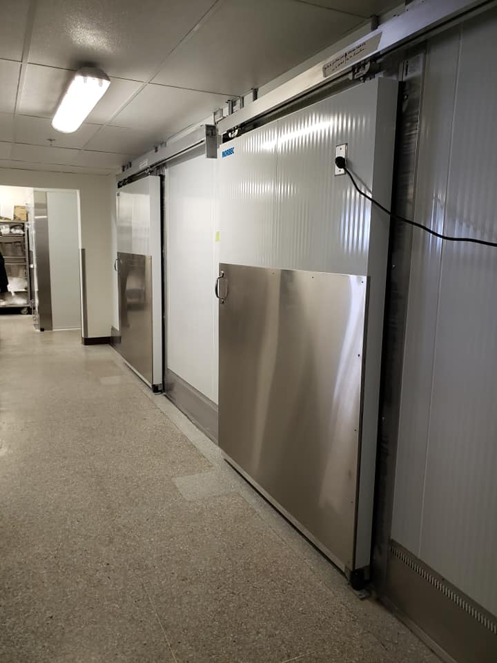 Une rangée de portes coulissantes en acier inoxydable dans une pièce.