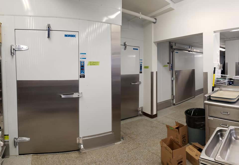 Une cuisine avec beaucoup d'électroménagers en inox et des caissons au sol.