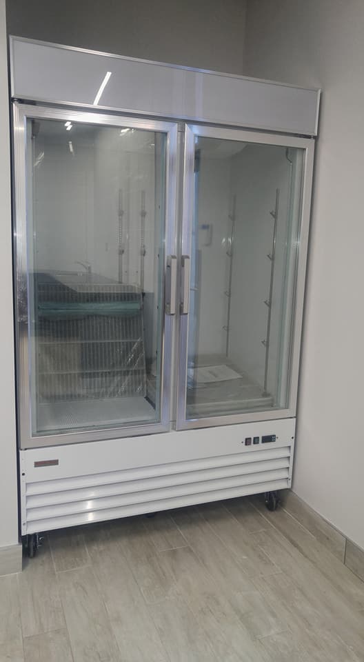 Un grand réfrigérateur à porte vitrée se trouve dans une pièce.