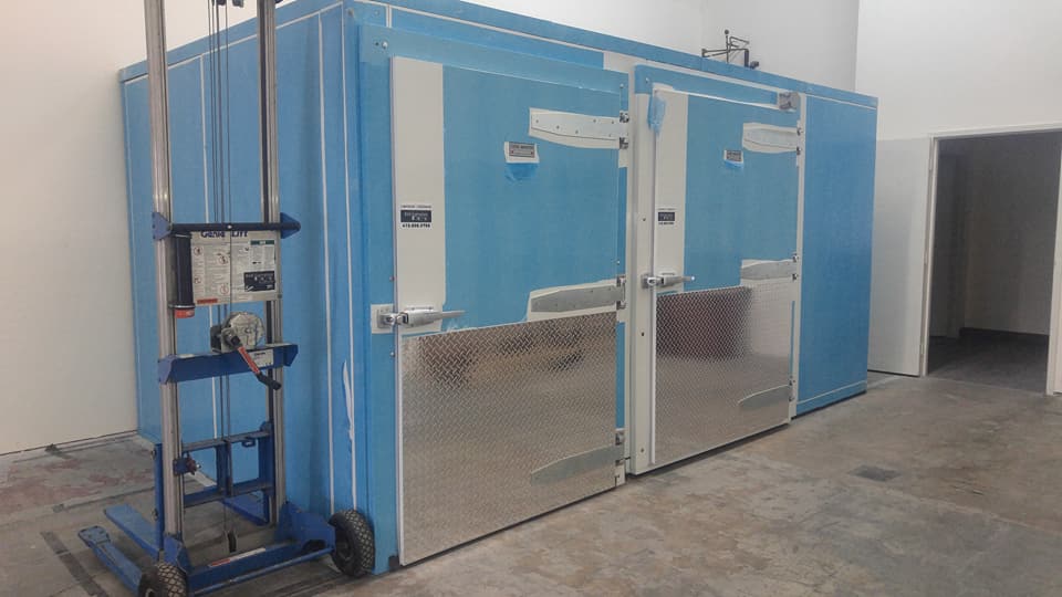 Un grand réfrigérateur bleu se trouve dans une pièce à côté d'un chariot.