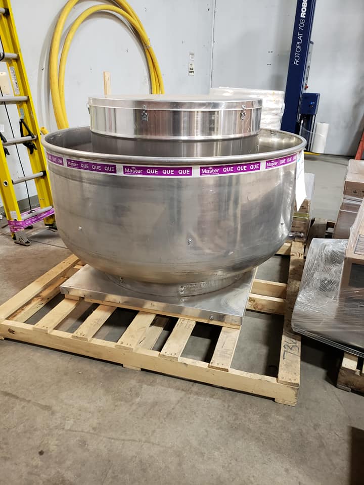 Un grand bol en acier inoxydable repose sur une palette en bois.