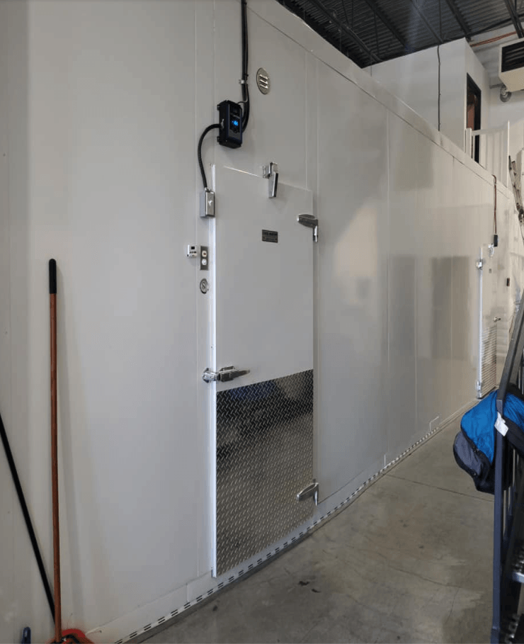 Une rangée de murs blancs dans une pièce avec un balai et un sac au sol.