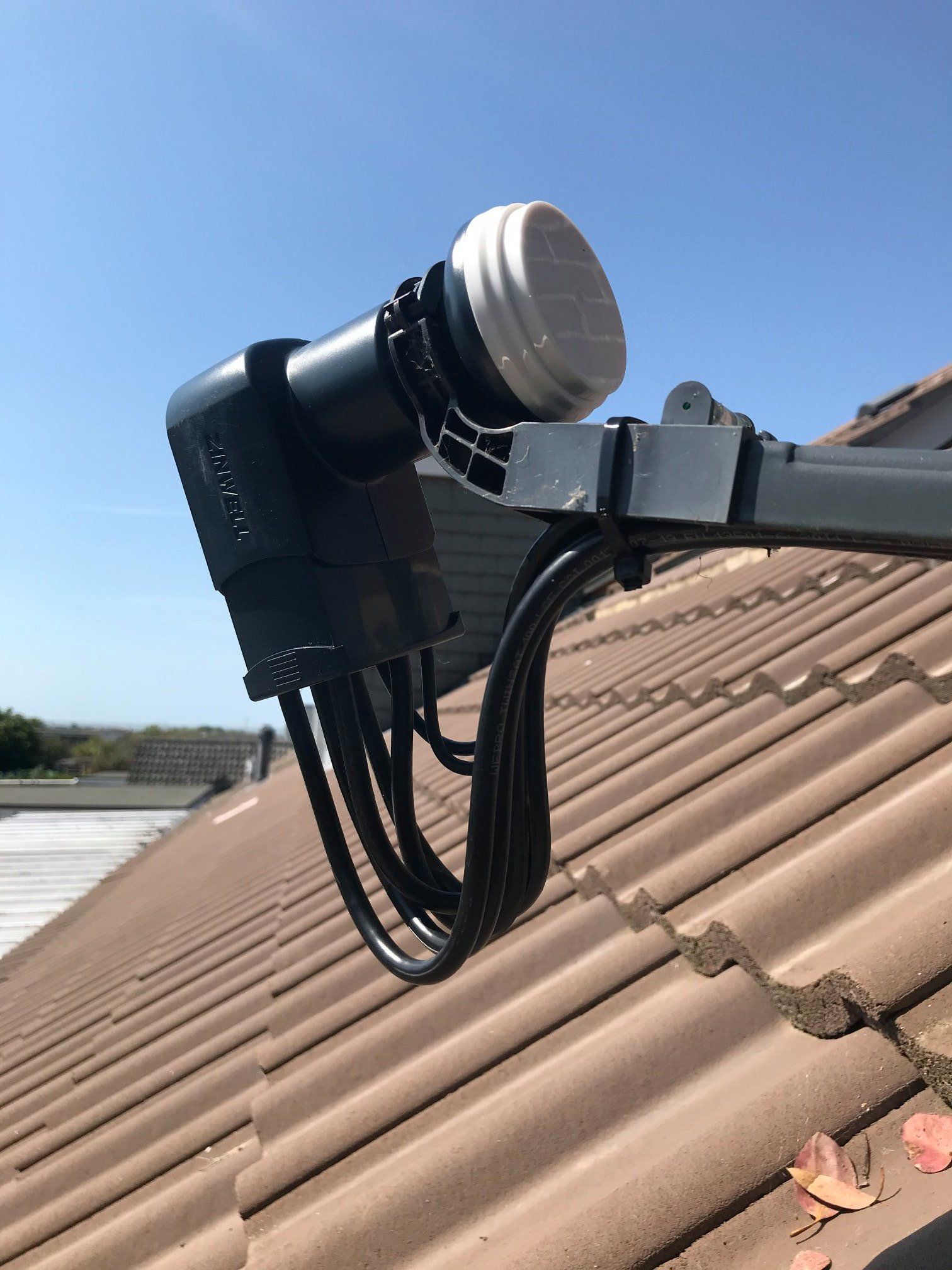 Close-up of a satellite receiver that is fixed to a dish on a roof.