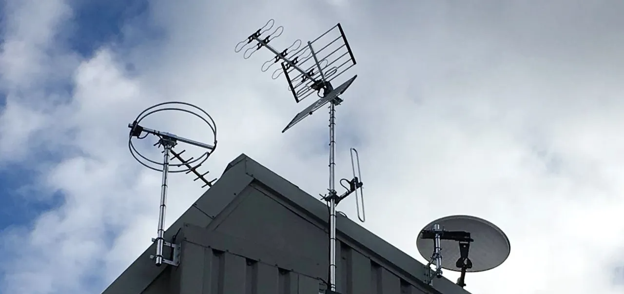 Satellite dish and tv antenna on a roof.