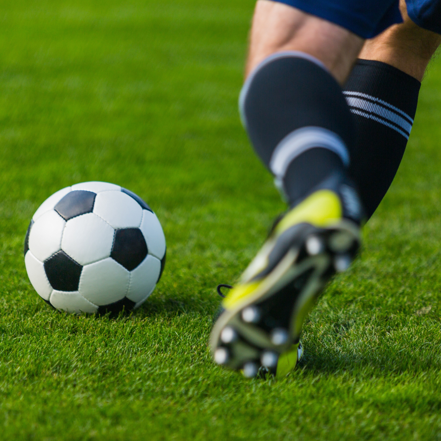 Soccer player kicking a black and white ball on a green grass field.
