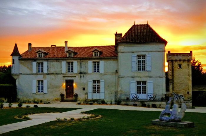 Une grande maison avec une statue devant elle au coucher du soleil