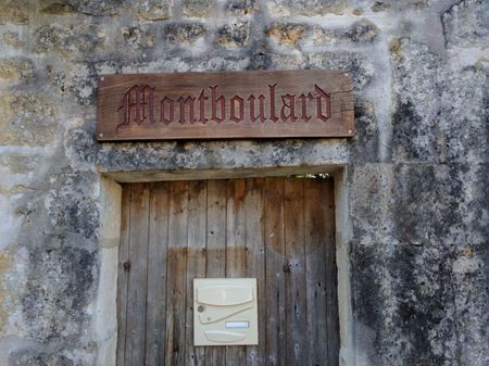 Un panneau en bois sur un mur en pierre dit montboulard