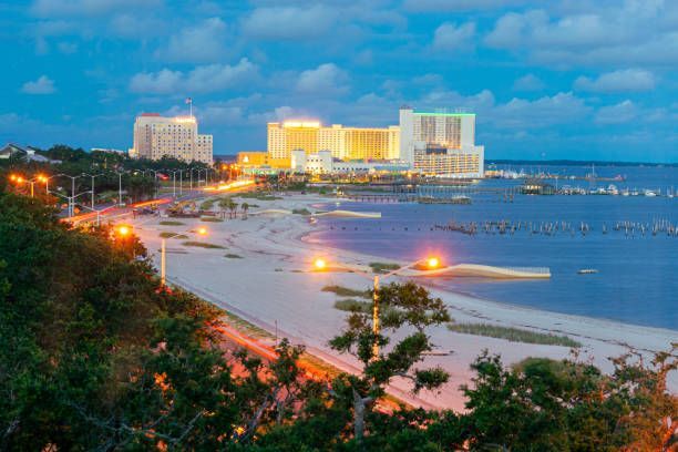 An aerial view of a beach in biloxi, mississippi at night with the Beau Rivage Casino in the background