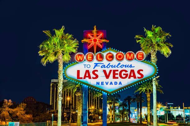 A welcome to fabulous las vegas sign is lit up at night surrounded by palm trees.