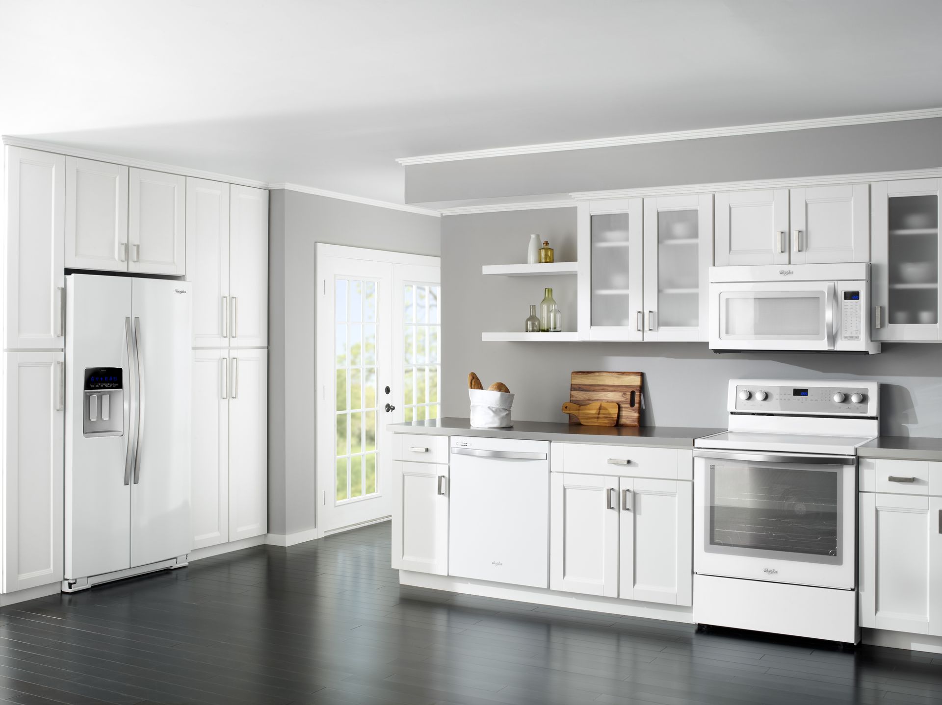 Modern white kitchen with stainless steel appliances, white cabinetry, open shelving, and dark wood flooring.