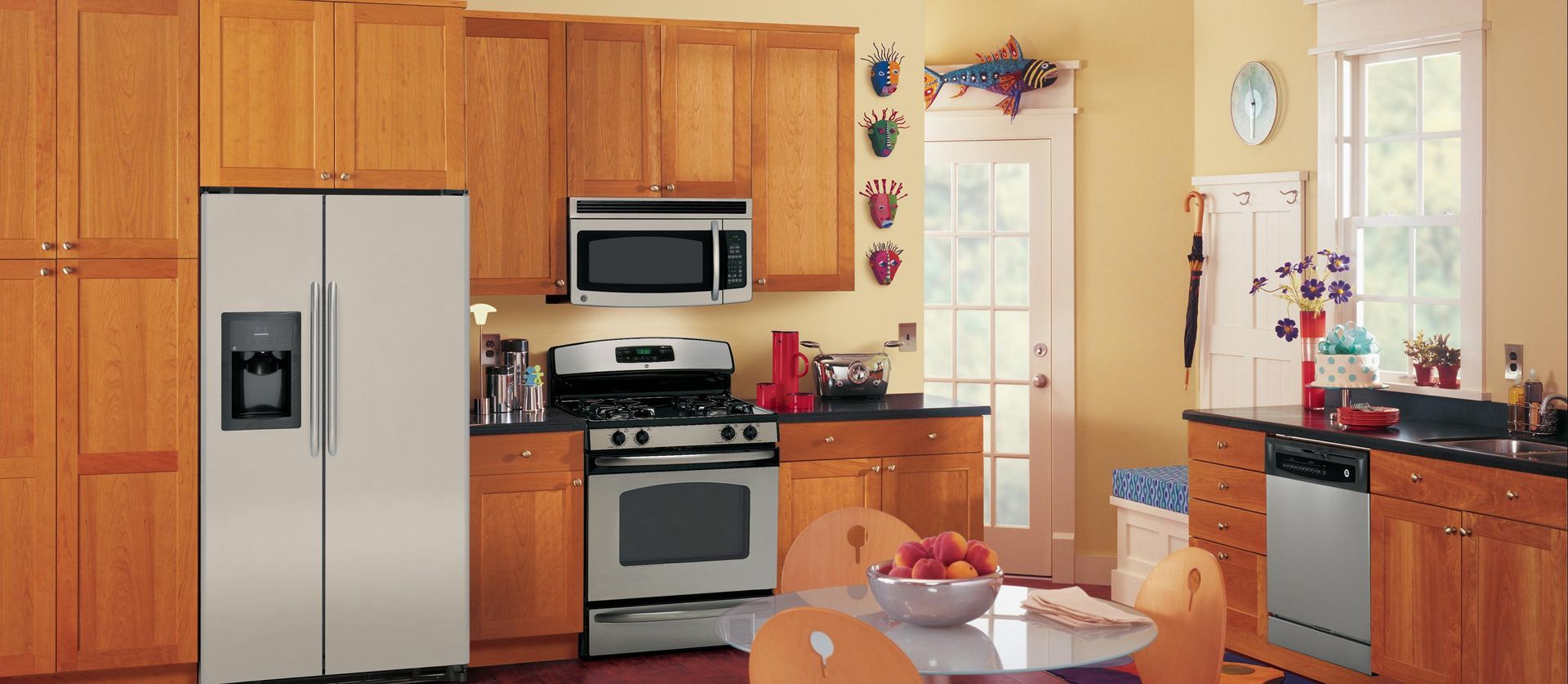 A kitchen with wooden cabinets, stainless steel appliances, a center dining table, and a glass door leading outside.