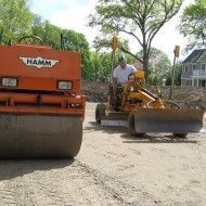 a man is driving a roller and a bulldozer on a dirt road