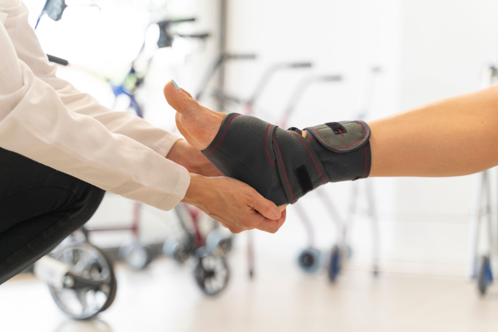 Doctor examining ankle brace on a patient's foot. Rehabilitation setting with walkers.