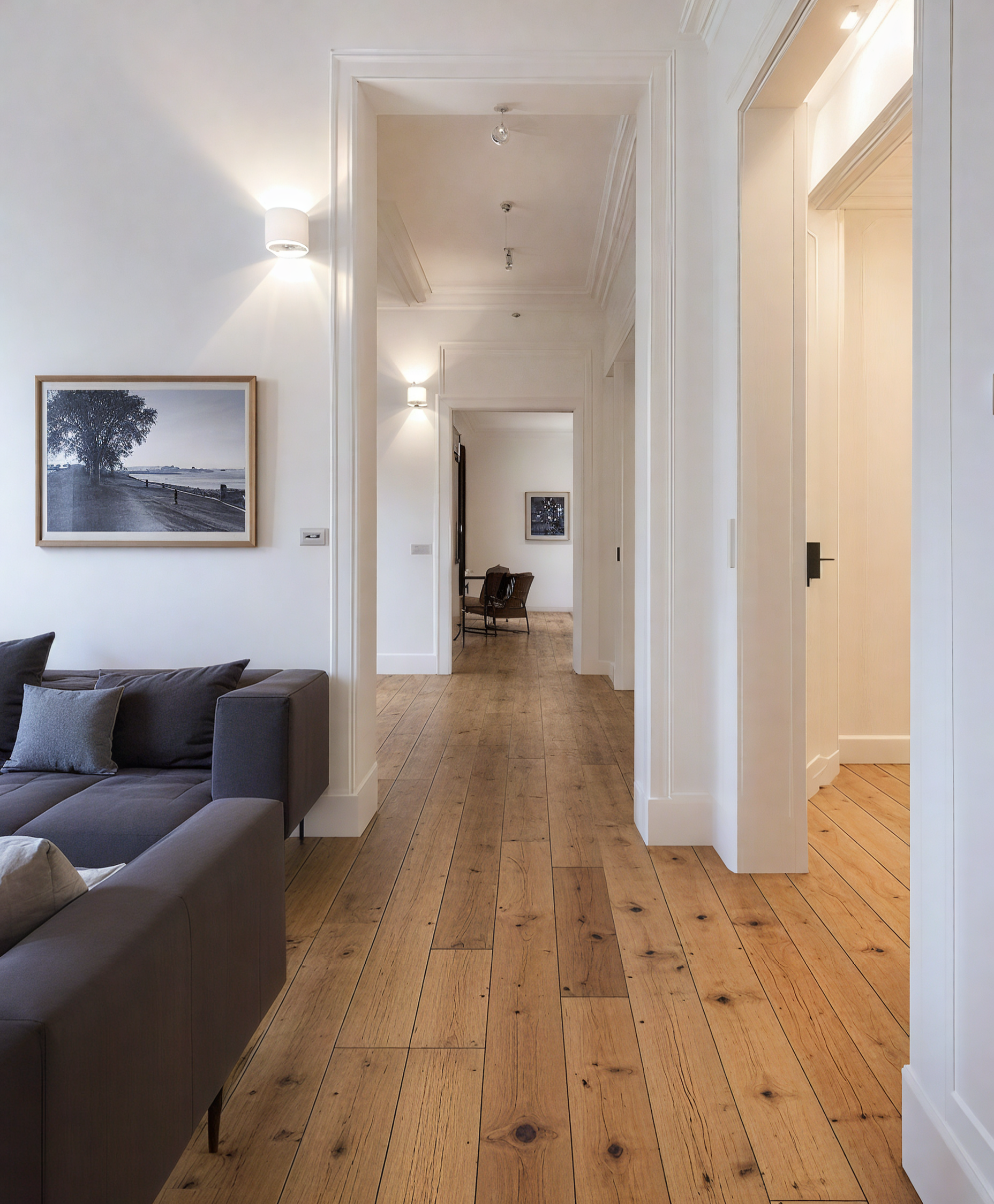 A living room with a white couch and a wooden floor.