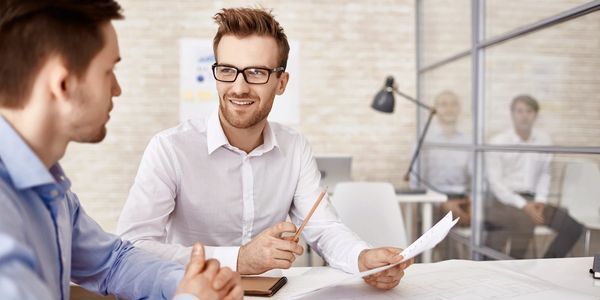 Two men are sitting at a table having a conversation.