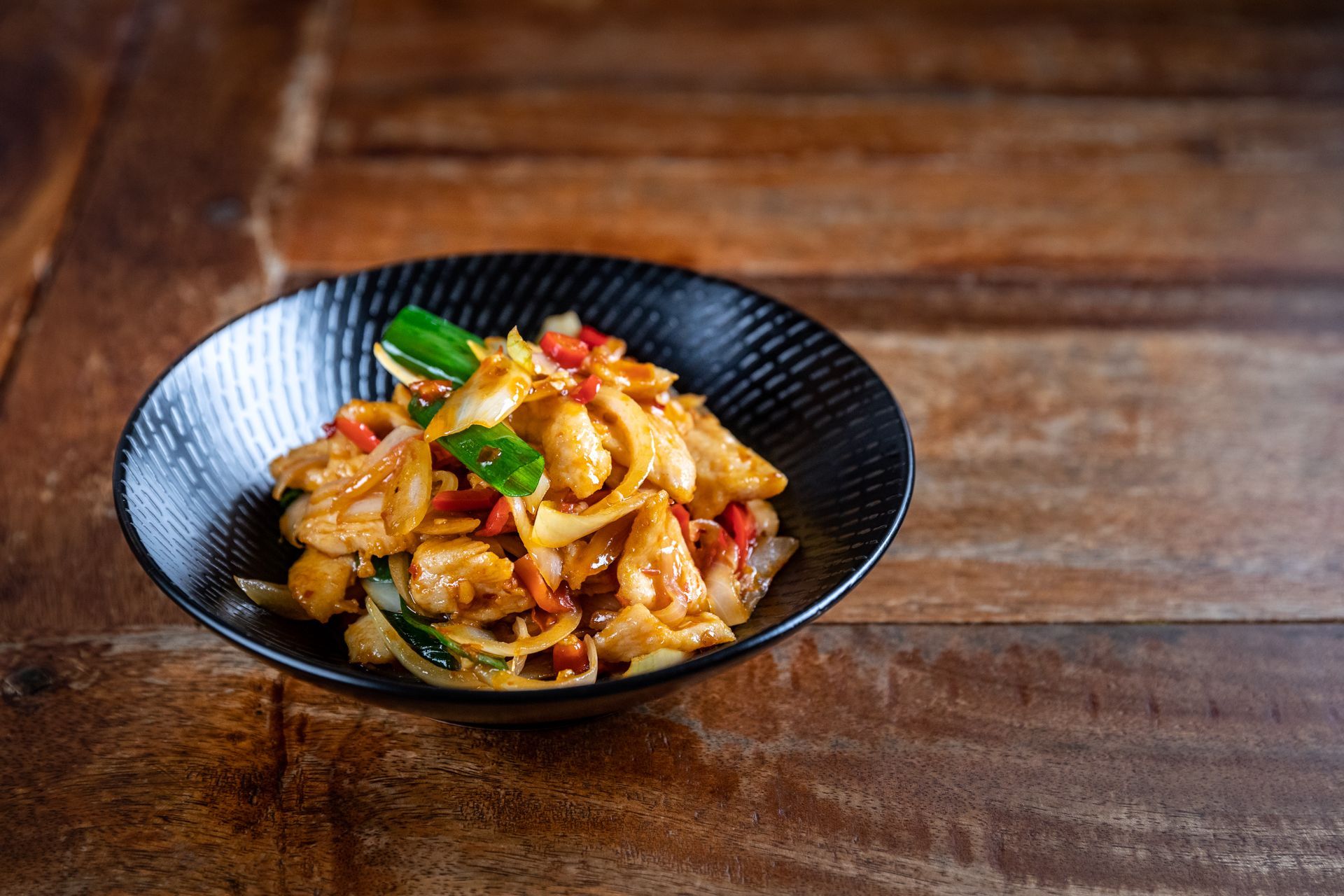 A bowl of food is sitting on a wooden table.