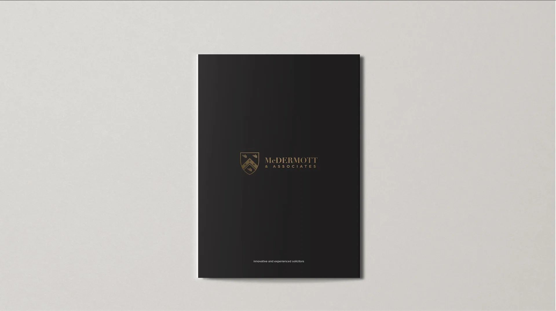 A black folder with a gold logo on it is sitting on a white surface.