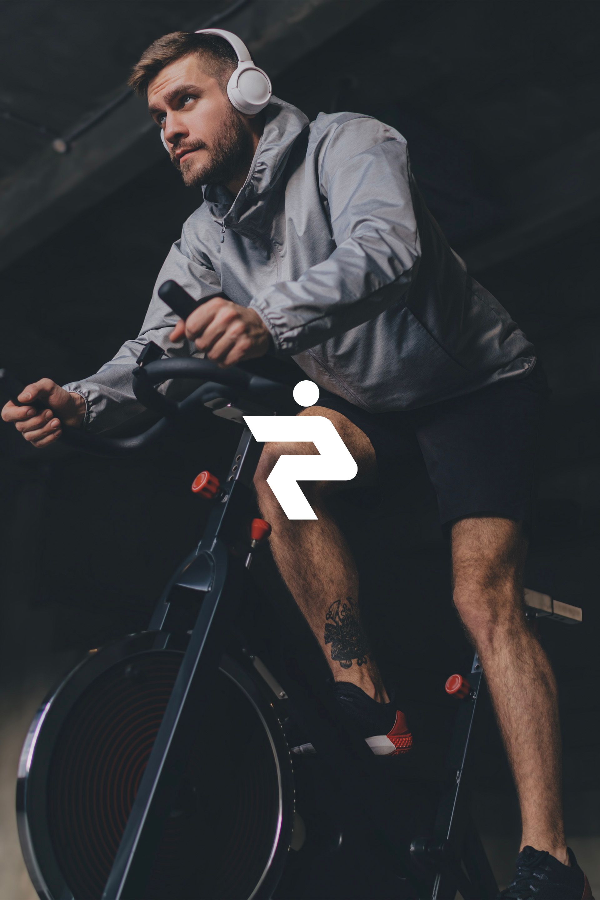 A man wearing headphones is riding an exercise bike.