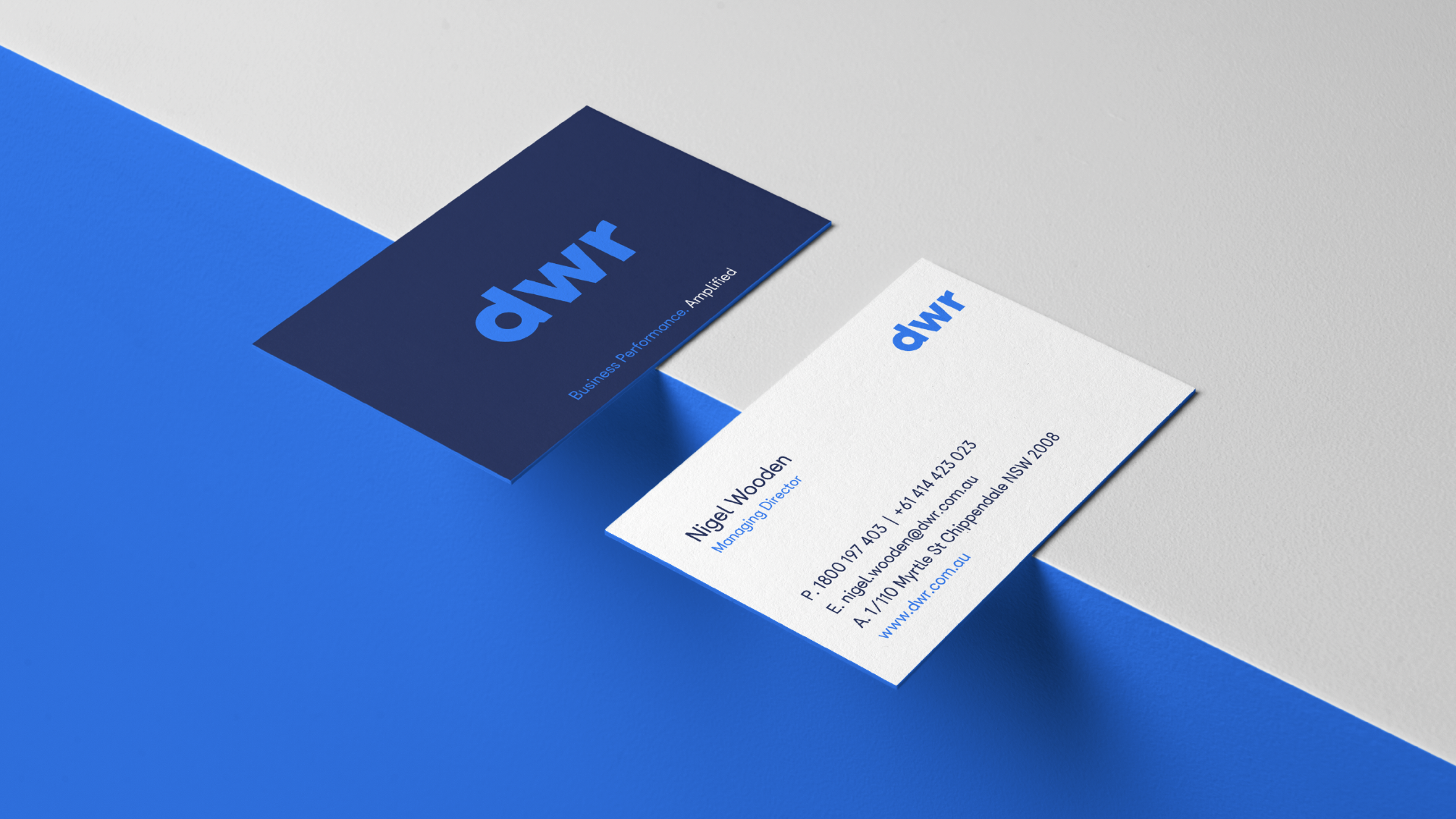 two business cards are sitting on top of each other on a blue and white surface .