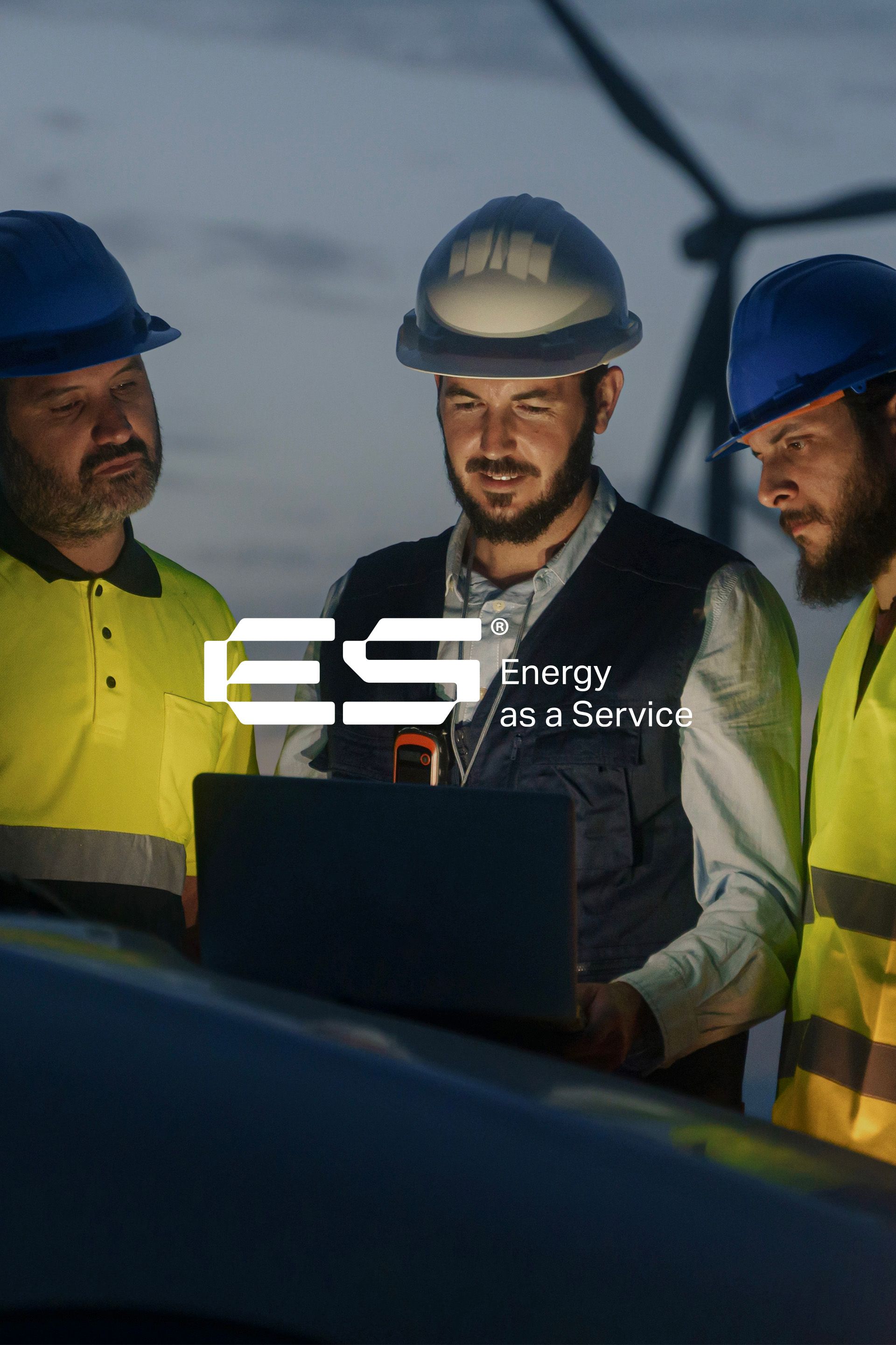 three men in hard hats are looking at a laptop computer .