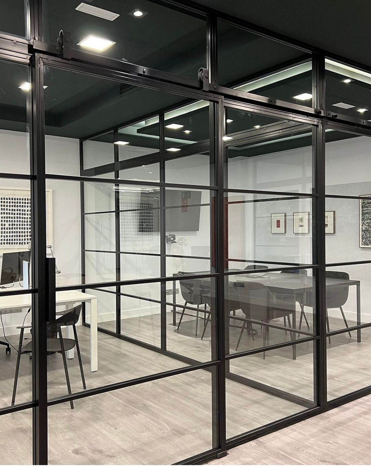 Una habitación con una mesa y sillas y una pared de cristal.