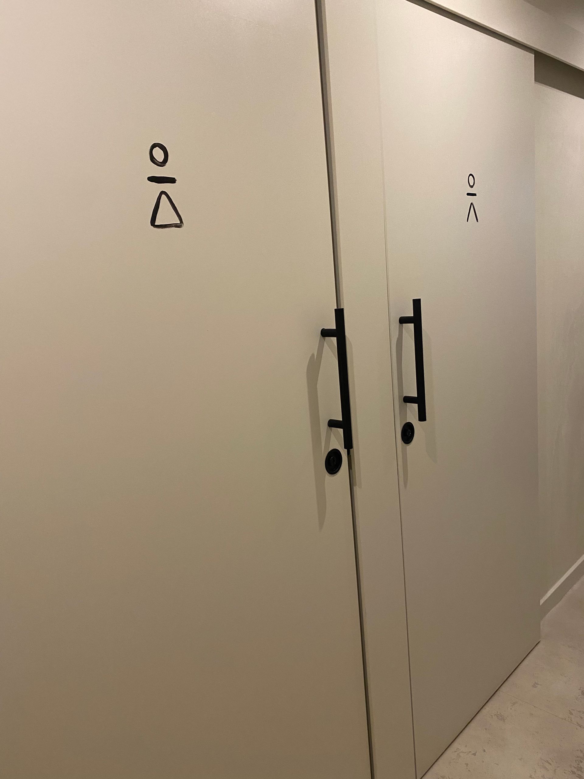 Una fila de puertas blancas con manijas negras en un pasillo.