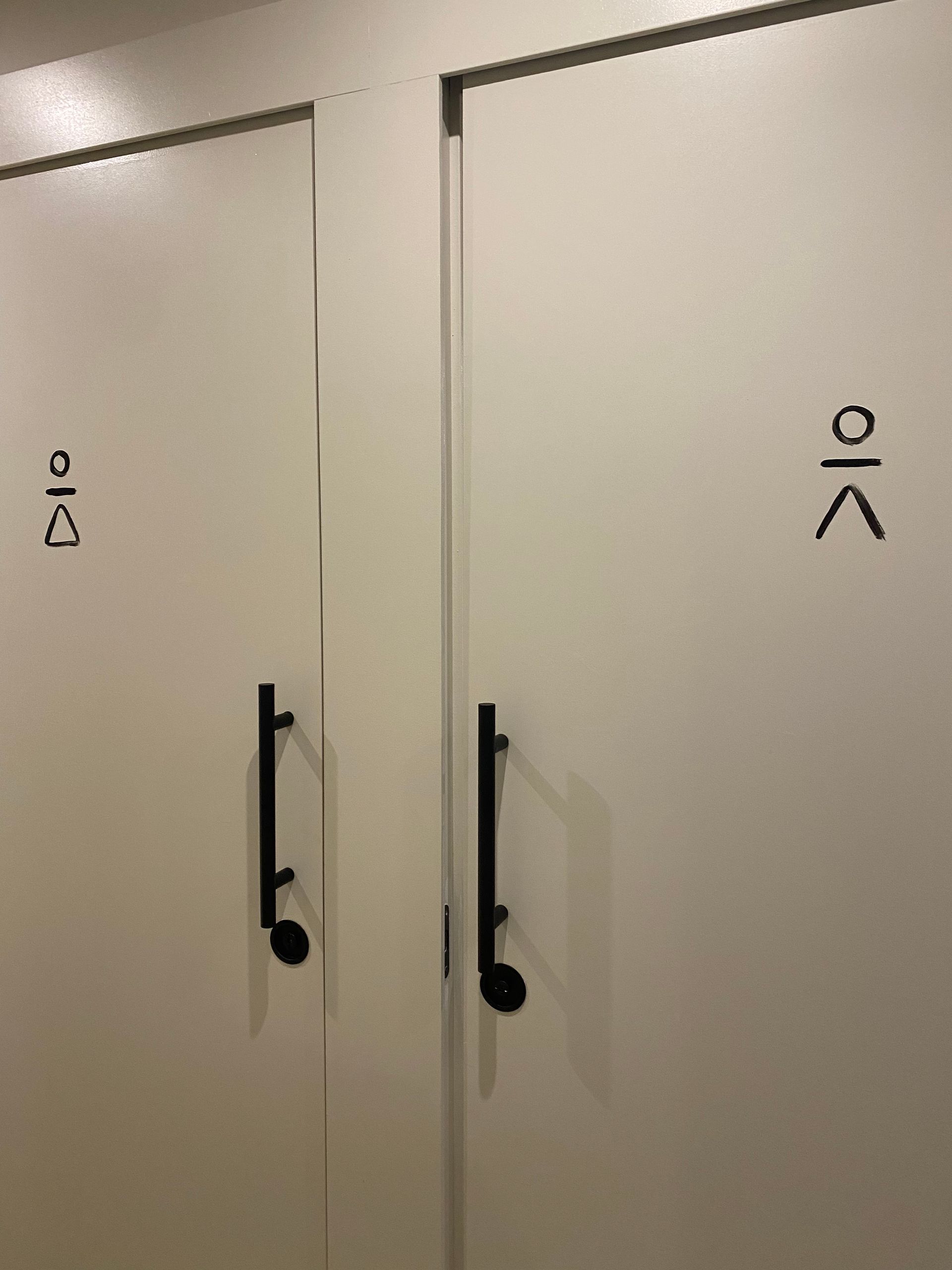 Dos puertas blancas con manijas negras y escritura coreana en ellas.