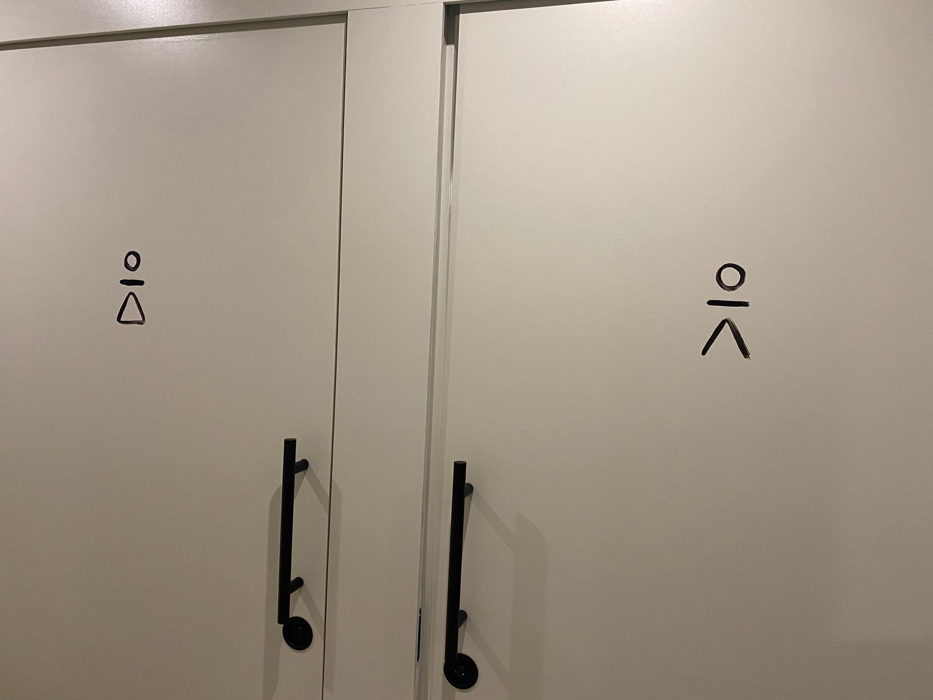 Dos puertas blancas con manijas negras y escritura china en ellas.