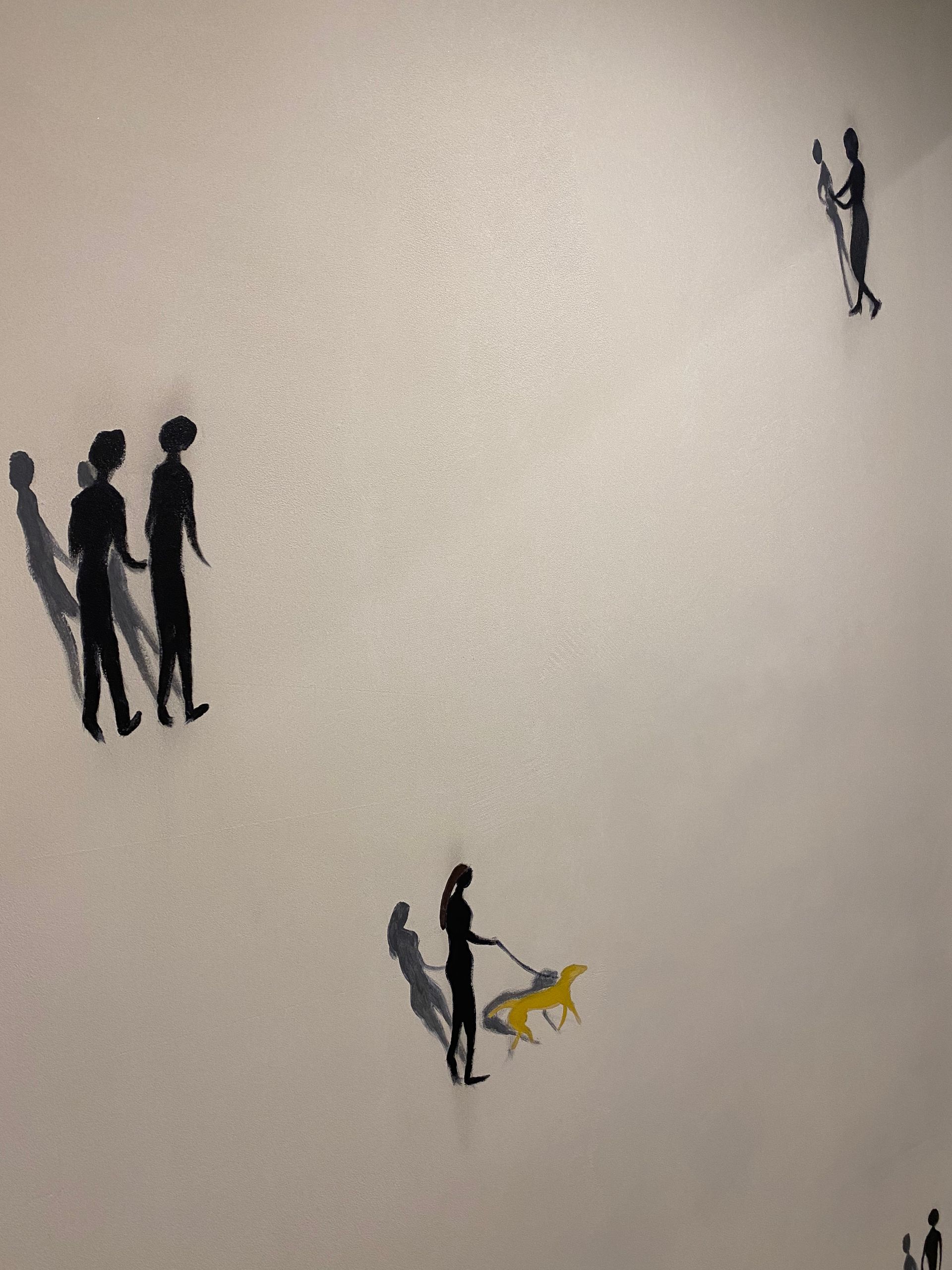 Sombras de personas y un perro en una pared.