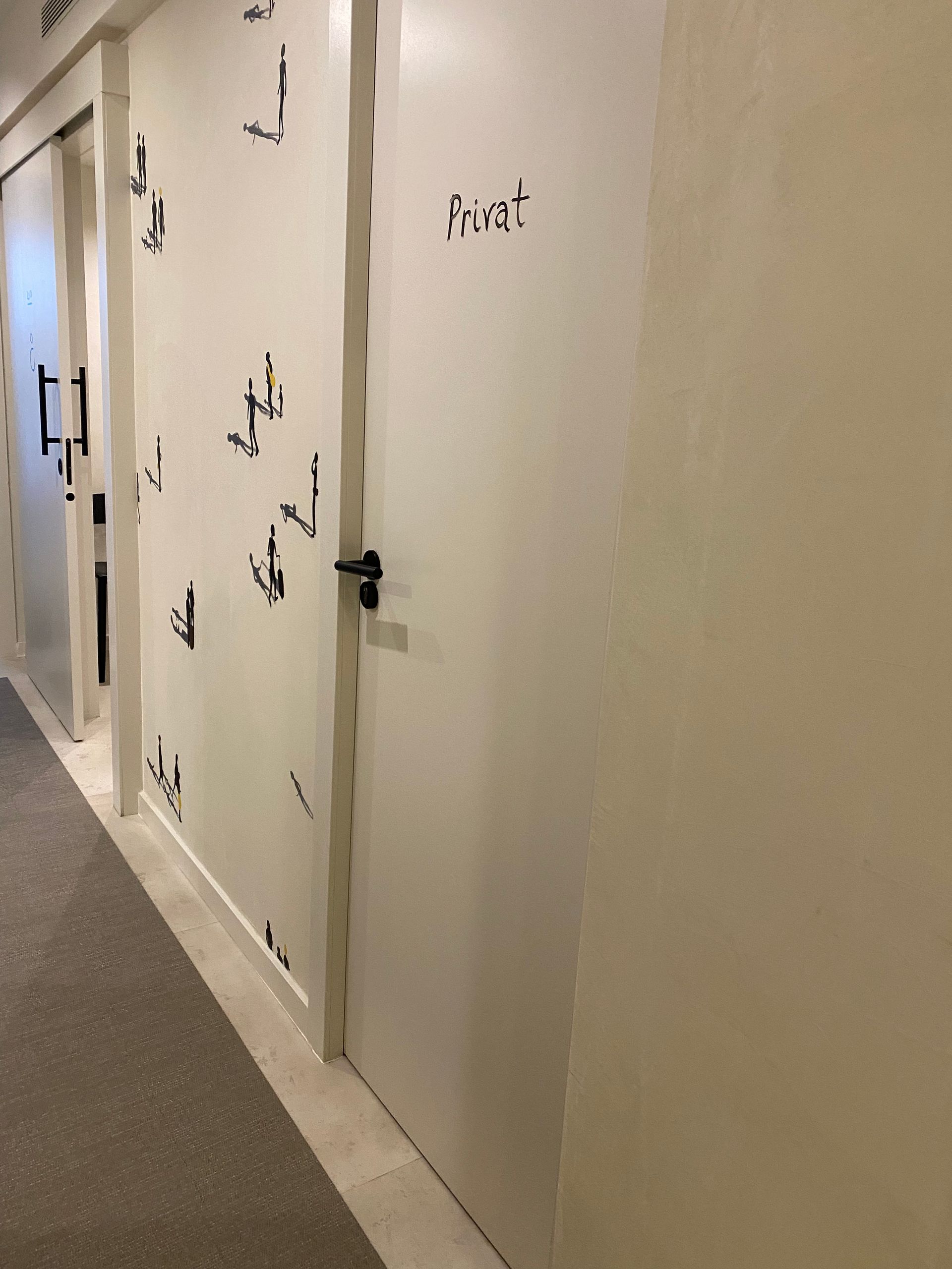 Un pasillo largo con puertas blancas y alfombra.