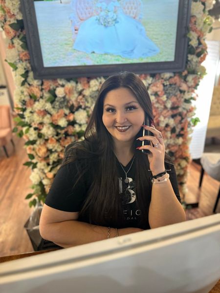 Bride in a white strapless gown looking in a lighted mirror, arranging her long, dark wavy hair.