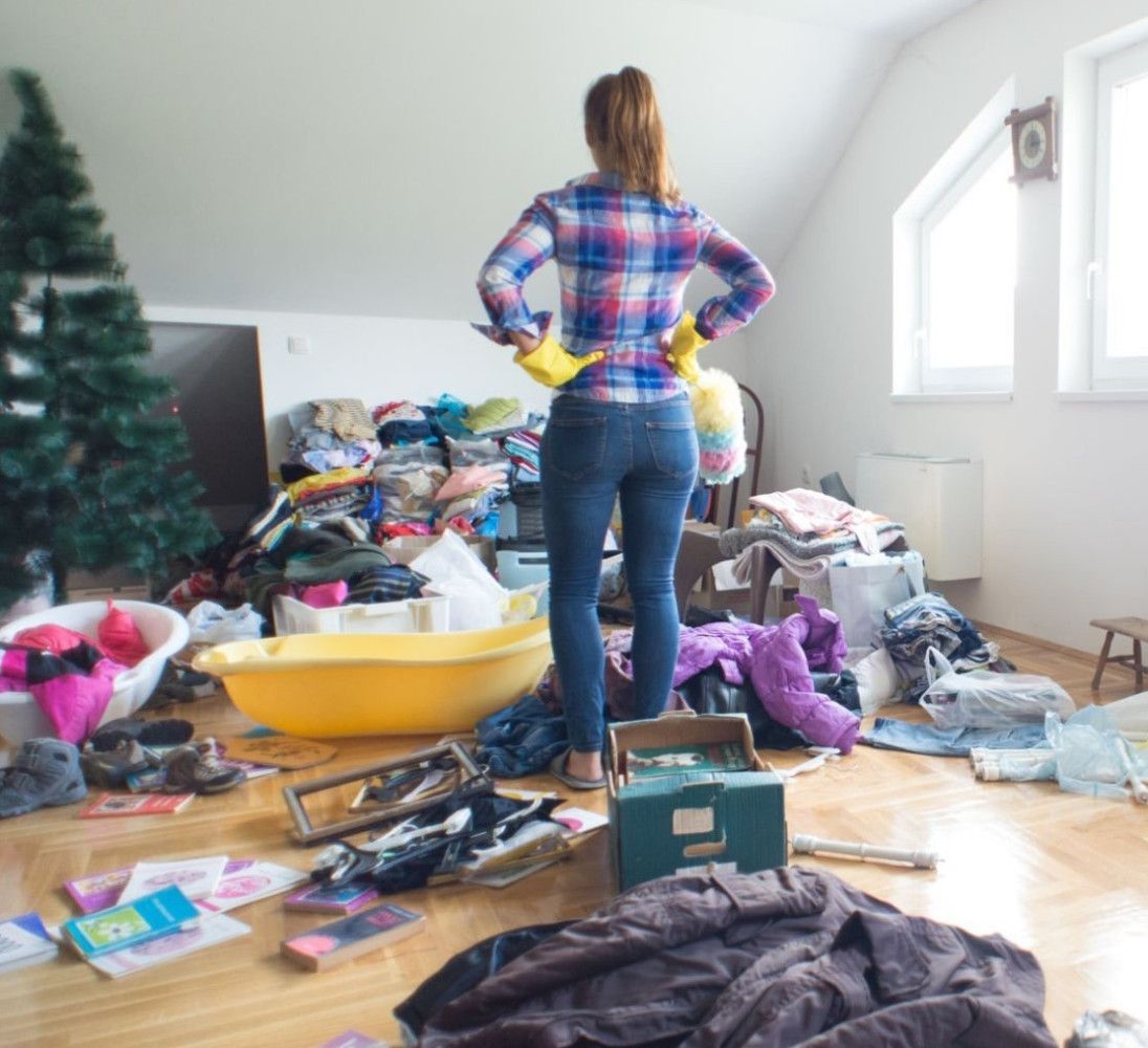 Netvarkingame kambaryje stovi moteris languotais marškiniais