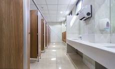Public restroom with wooden stalls, white sinks, and a paper towel dispenser.