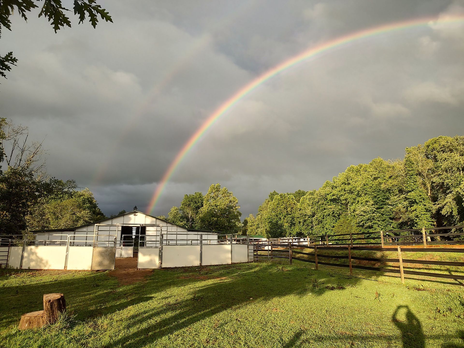 There is a rainbow in the sky over a fenced in area