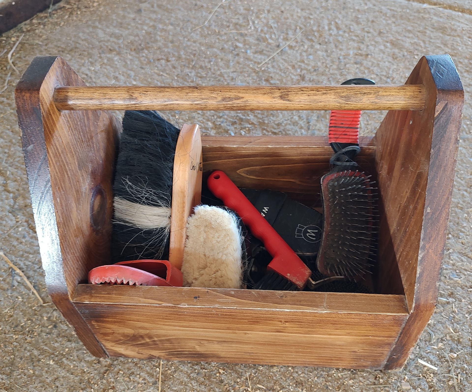 A wooden box filled with horse brushes and combs