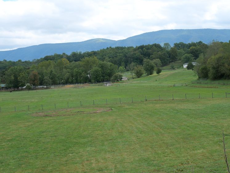 A grassy field with a barbed wire fence and mountains in the background