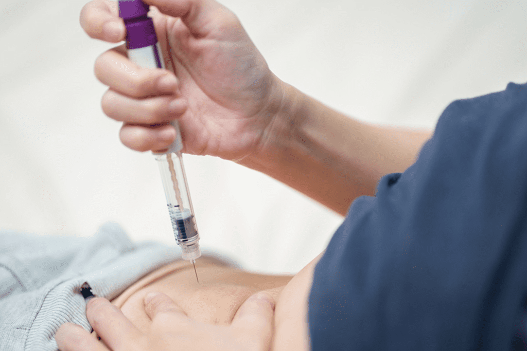 Person administering an injection into abdomen with a purple and clear syringe.