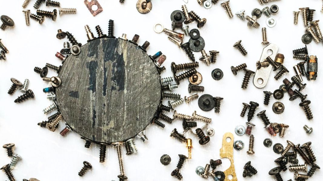 a magnet is surrounded by screws and washers on a white surface